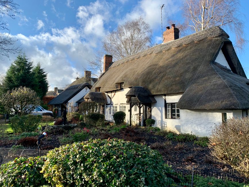 Whitewashed English country cottage with a dog at the doorway — typical Cottages.com pet-friendly property